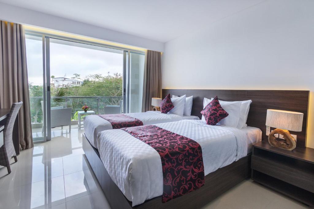 ein Hotelzimmer mit einem Bett und einem großen Fenster in der Unterkunft Adhiloka in Uluwatu