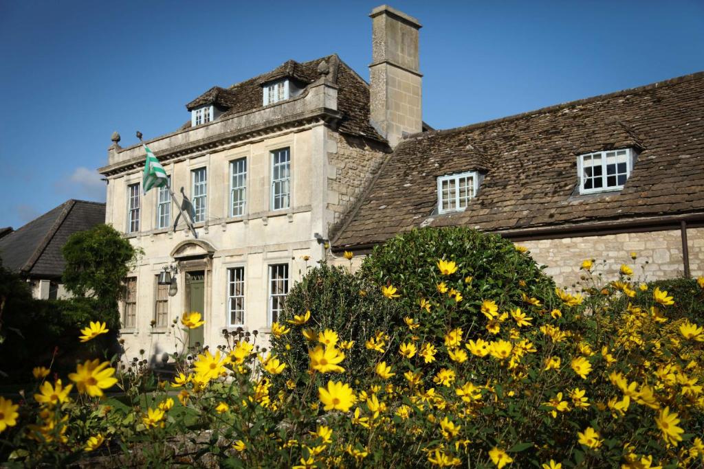 een oud huis met gele bloemen ervoor bij The Moonraker Hotel in Bradford on Avon