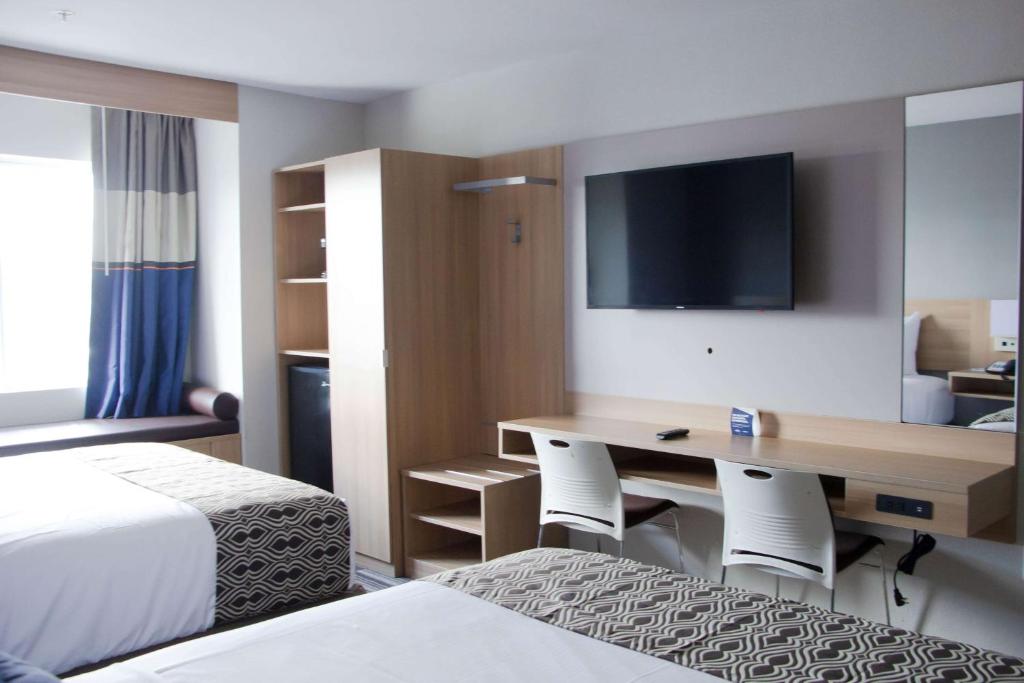 ein Hotelzimmer mit einem Schreibtisch und einem Bett in der Unterkunft Microtel Inn & Suites by Wyndham Camp Lejeune/Jacksonville in Jacksonville