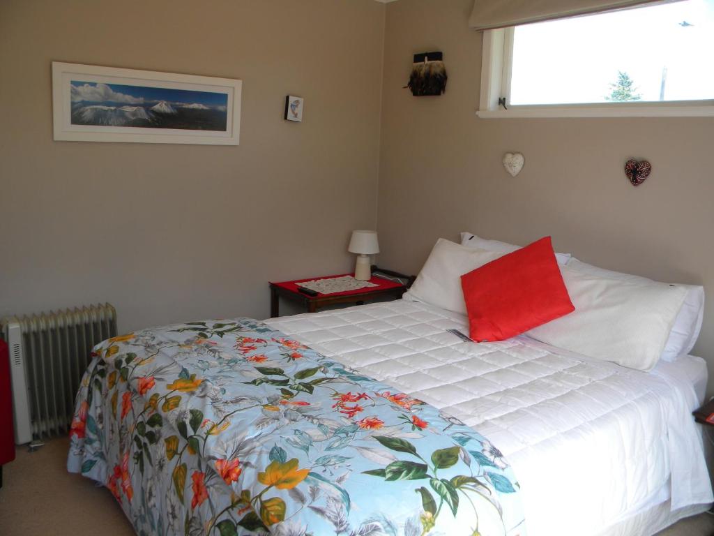 a bedroom with a bed with a red pillow on it at b&b @ fynnz in Turangi