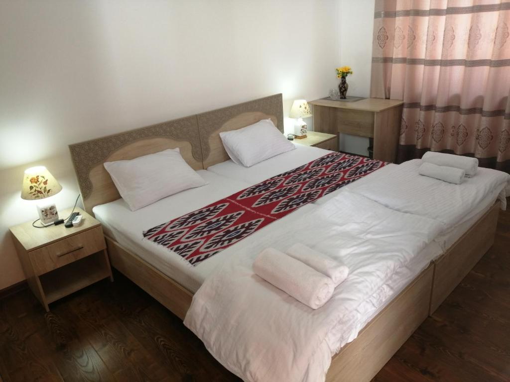 1 dormitorio con 1 cama grande con sábanas y almohadas blancas en Anis-Pari Hotel en Bukhara