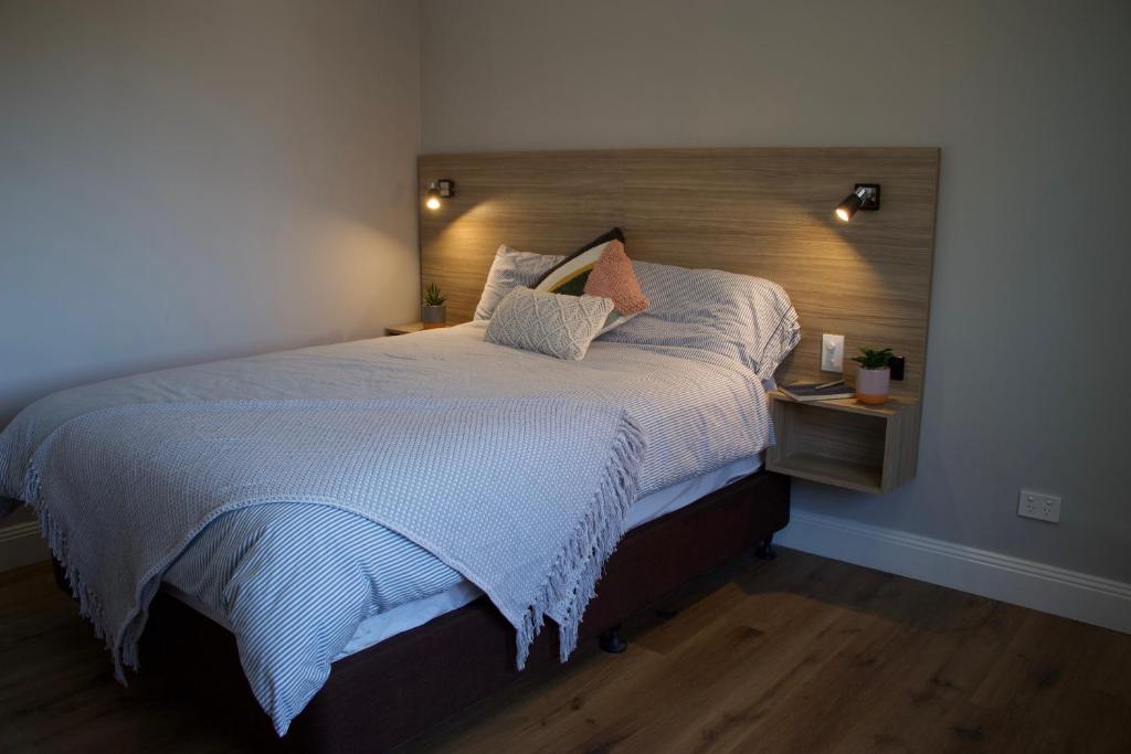 a bedroom with a large bed with a wooden headboard at Carnarvon Lodge Kirribilli, Sydney in Sydney