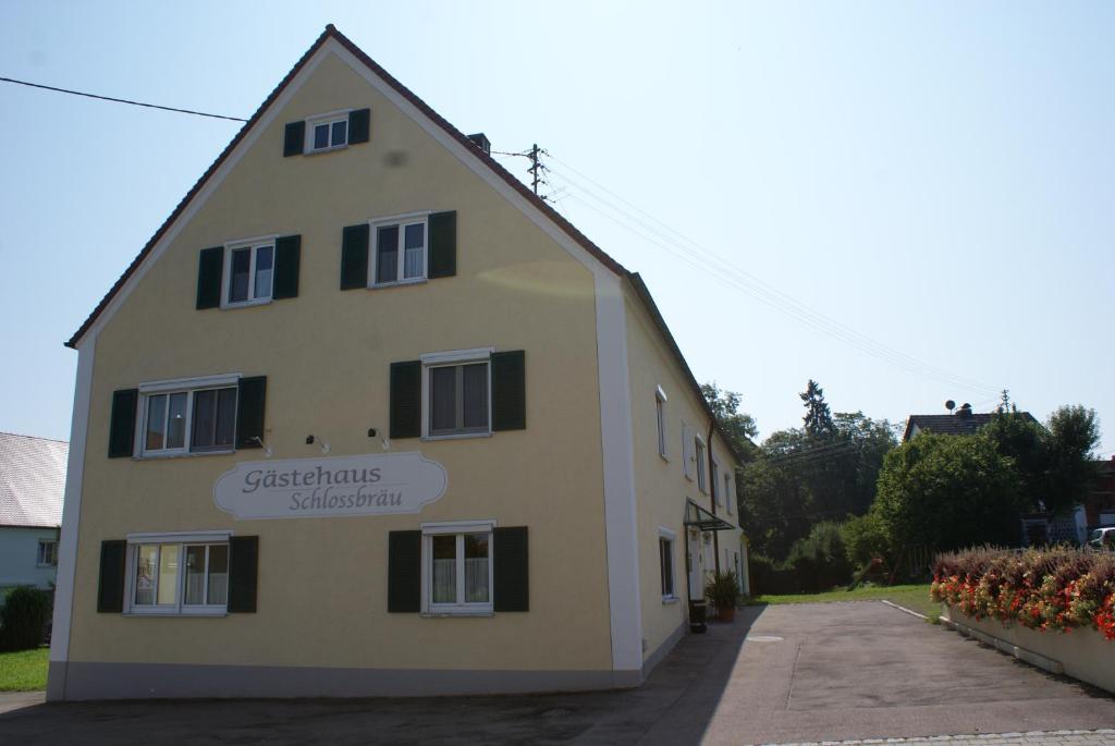 un bâtiment avec un panneau sur son côté dans l'établissement Gästehaus Schlossbräu, à Autenried