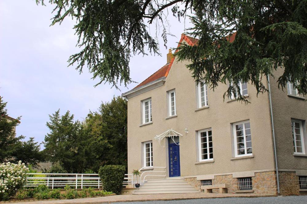 een groot huis met een blauwe deur en een trap bij La Maison du Parc in Les Épesses