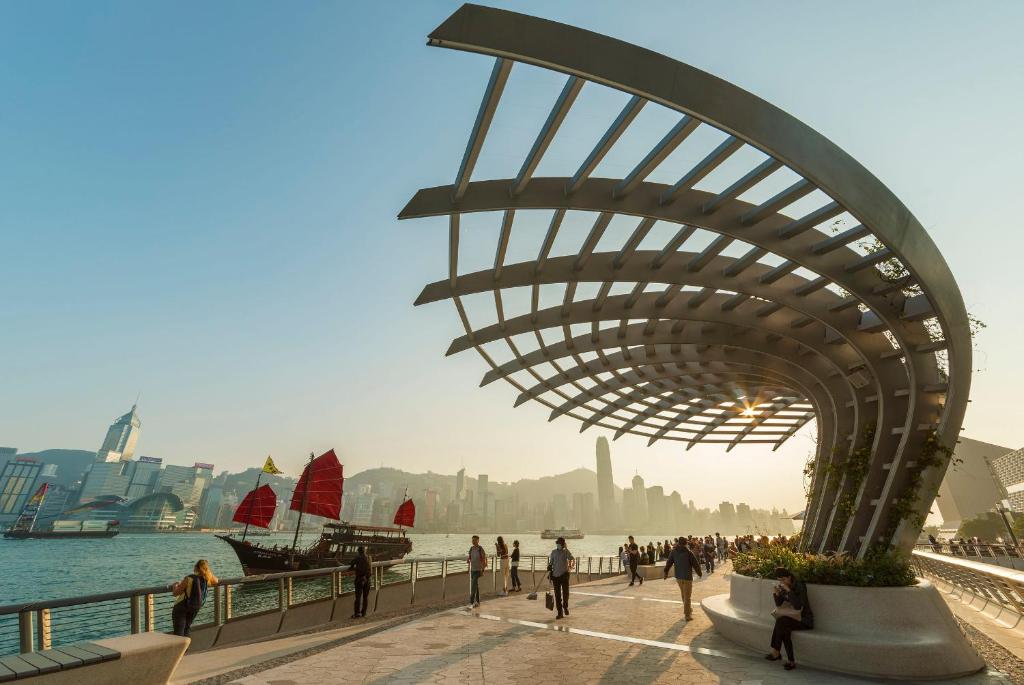 un gruppo di persone che camminano su un marciapiede vicino all'acqua di Dash Living on Prat a Hong Kong