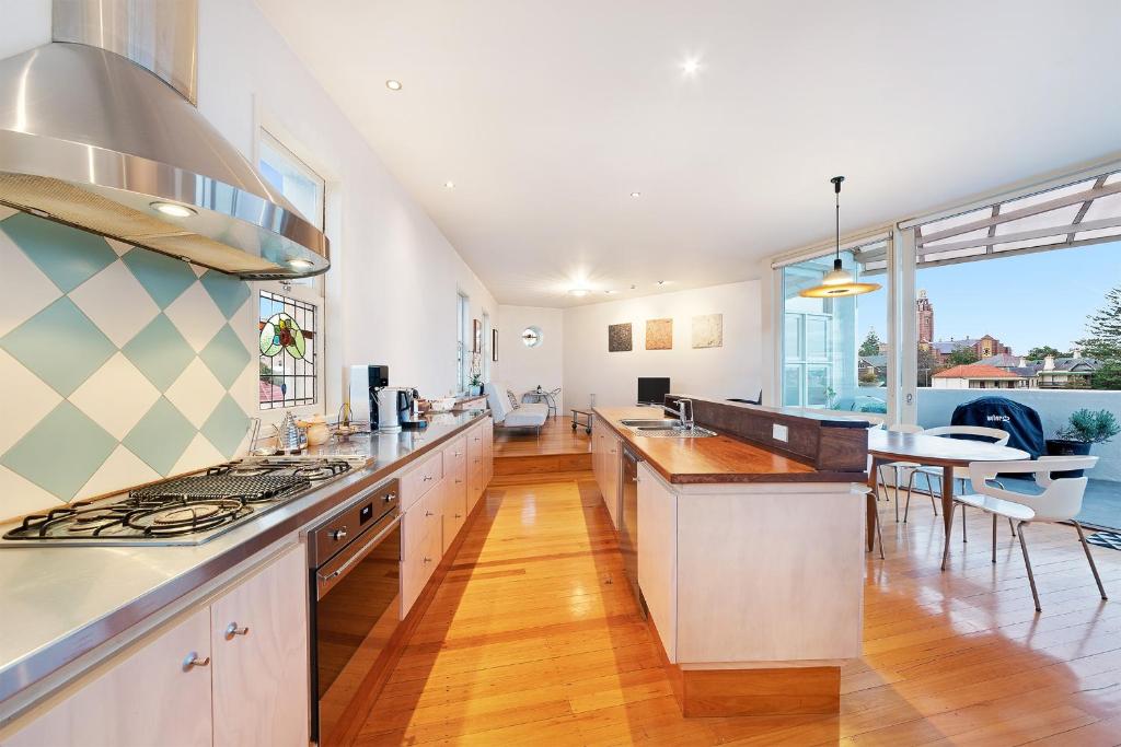 une cuisine avec des placards blancs et une salle à manger dans l'établissement Coastal Penthouse at Coogee Beach, à Sydney