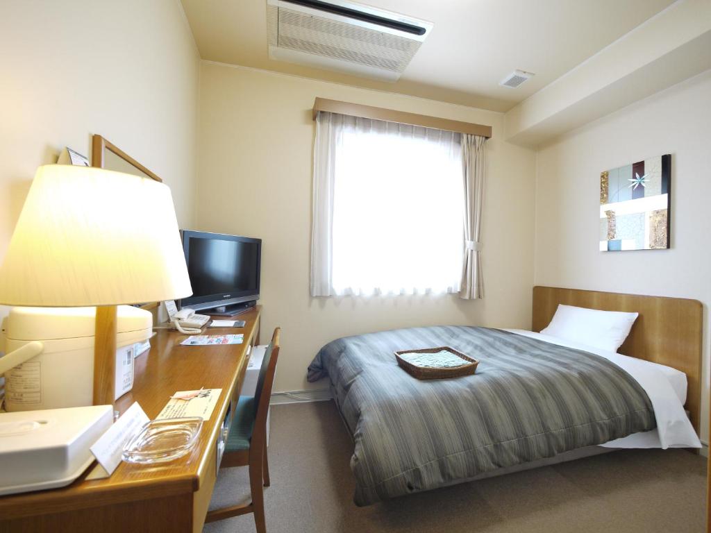 a hotel room with a bed and a desk with a computer at Hotel Route-Inn Kani in Kani