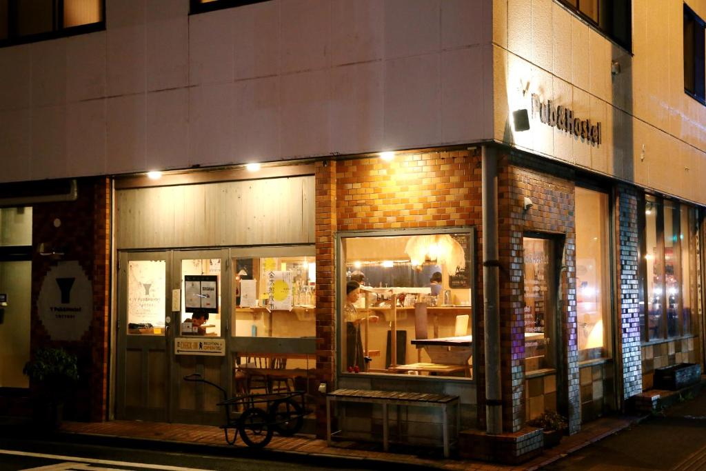 un magasin devant un bâtiment en briques la nuit dans l'établissement Y Pub & Hostel Tottori, à Tottori