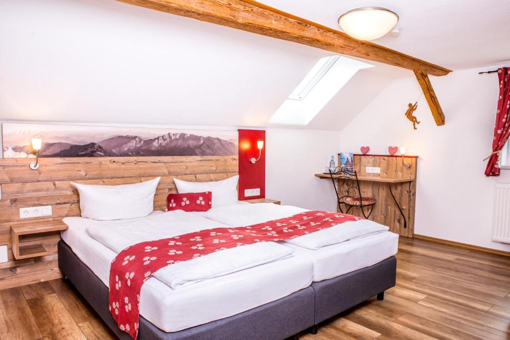una camera con un grande letto in una stanza con pavimenti in legno di Traditions-Gasthaus Bayrischer Hof a Leutkirch im Allgäu