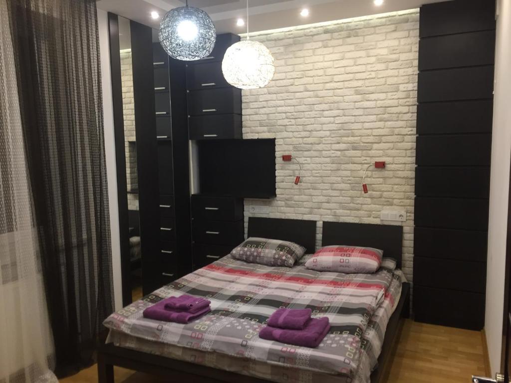 a bedroom with a bed with purple pillows on it at Затишні апартаменти в центрі міста in Ternopilʼ