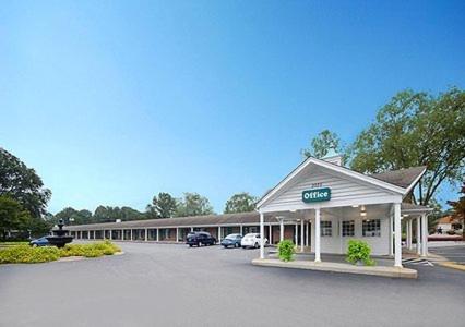 una tienda en un estacionamiento con coches aparcados delante en Ambassador Inn en Fayetteville