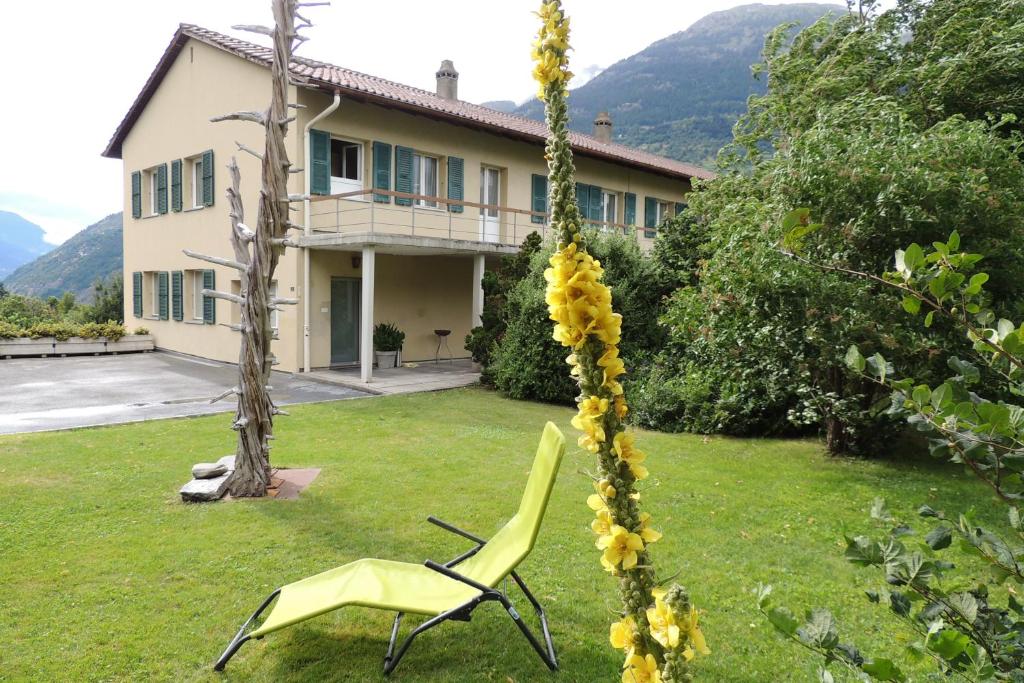 a yellow chair in the yard of a house at B&B Haus Schönstatt contactless- Check-In in Brig