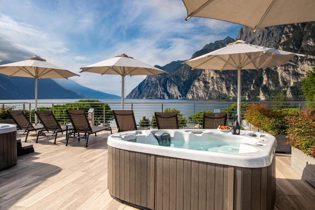 uma banheira de hidromassagem num deque com cadeiras e guarda-sóis em Hotel Bellariva em Riva del Garda