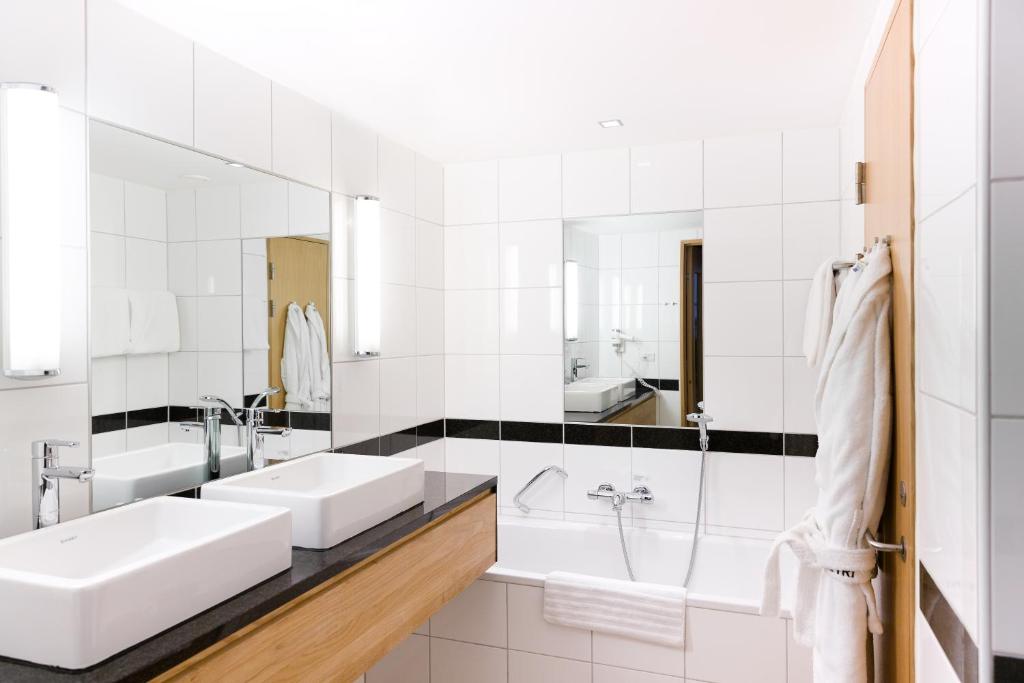 a white bathroom with two sinks and a tub at Hotel Skt Petri in Copenhagen