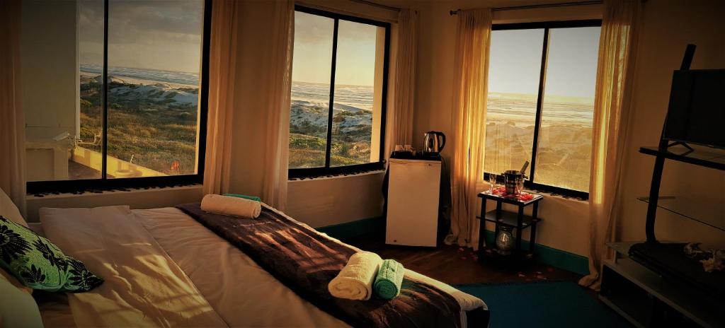 een slaapkamer met grote ramen en een bed met handdoeken erop bij Beachmusic in Kaapstad