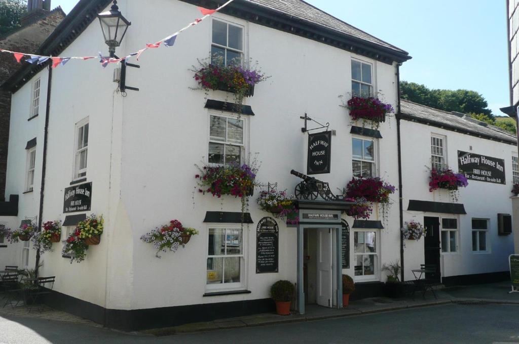 un bâtiment blanc avec des boîtes de fleurs à l'avant dans l'établissement Halfway House Inn, à Kingsand