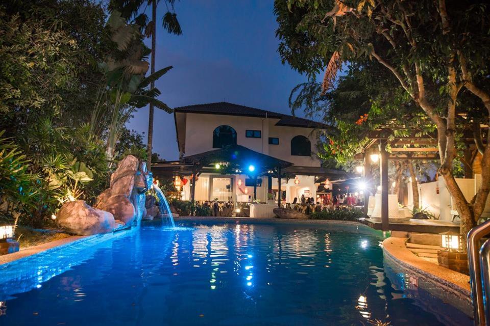 - une piscine avec une fontaine en soirée dans l'établissement Tanjung Villa, à Muar