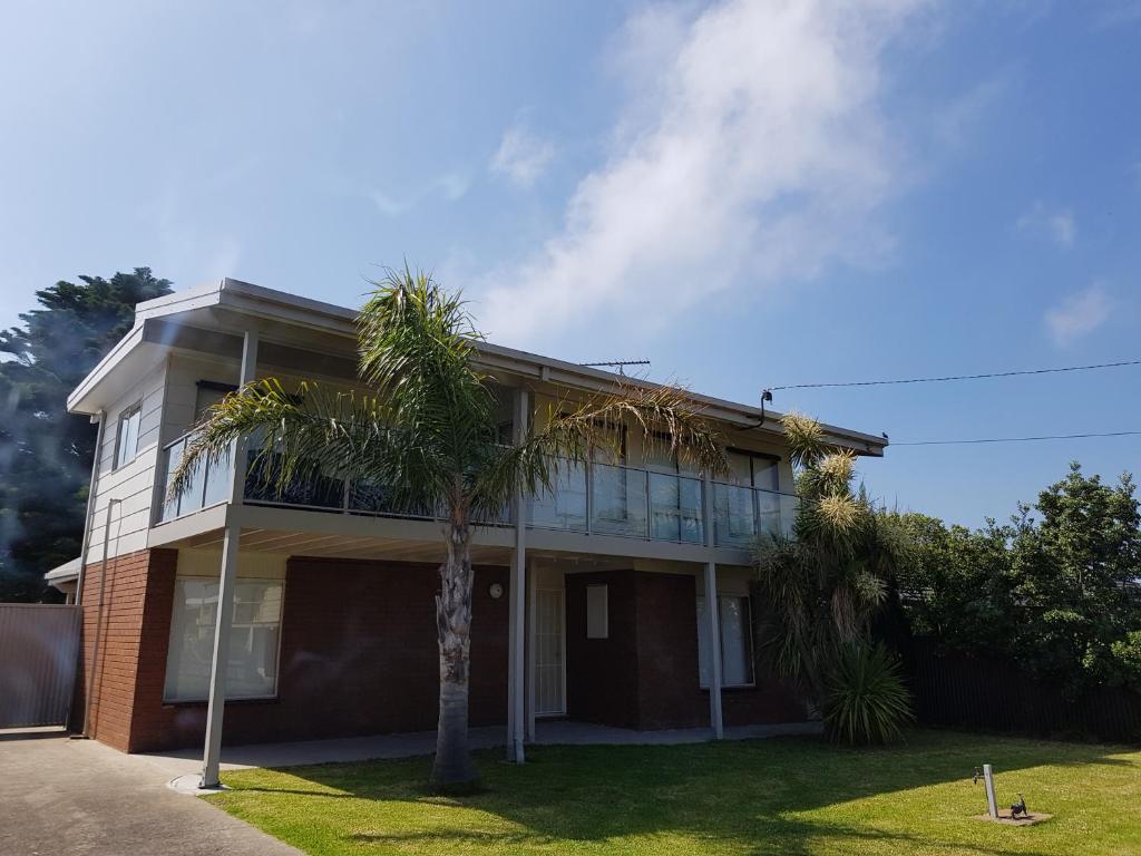 uma casa com uma palmeira em frente em Portarlington beach shack 50 metres to the water em Portarlington