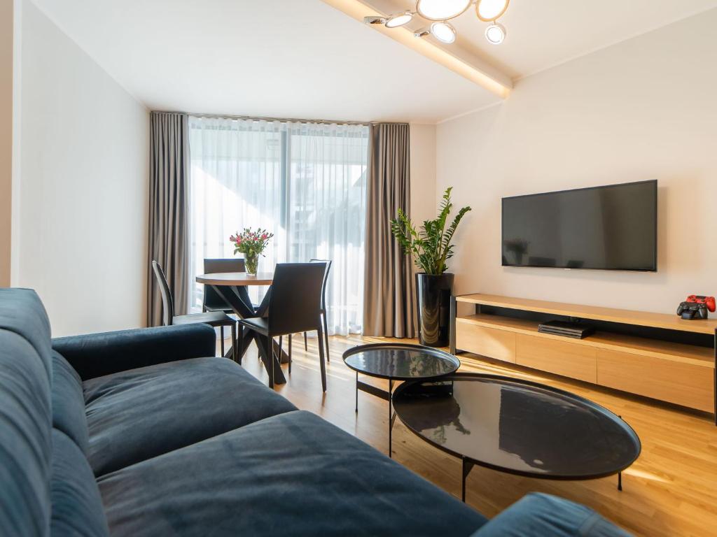 a living room with a blue couch and a tv at Apartament Prywatny Seaside Park Rackiewicz in Kołobrzeg