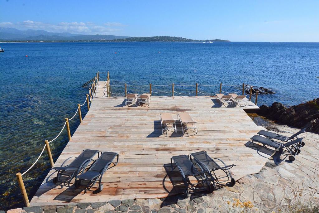 a group of chairs sitting on a dock in the water at Résidence U Paviddonu in Porto-Vecchio