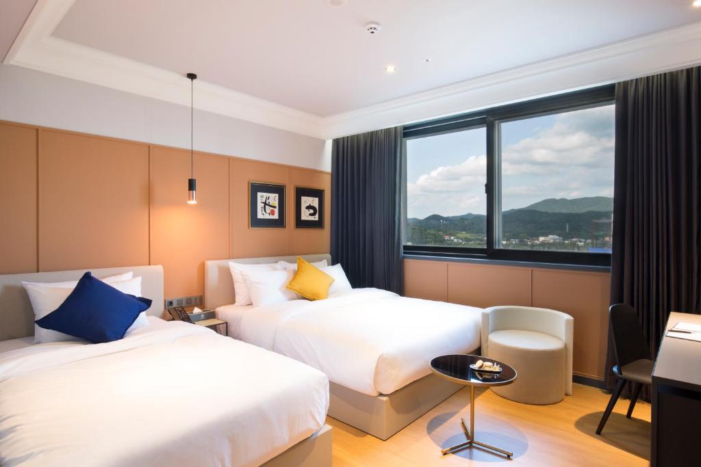 Habitación de hotel con 2 camas y ventana en Brown Dot Hotel Jinju, en Jinju