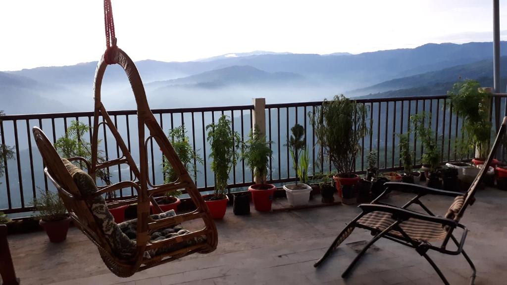 una silla y macetas en un balcón con vistas en The River View Homestay en Kurseong