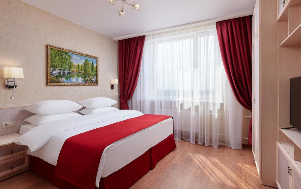 a bedroom with a large bed with red curtains at Hanoi-Moscow Aparthotel in Moscow