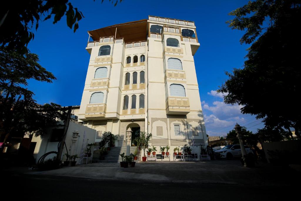 un grand bâtiment blanc avec une tour d'horloge dans l'établissement Hotel Ratangarh Palace, à Jaipur