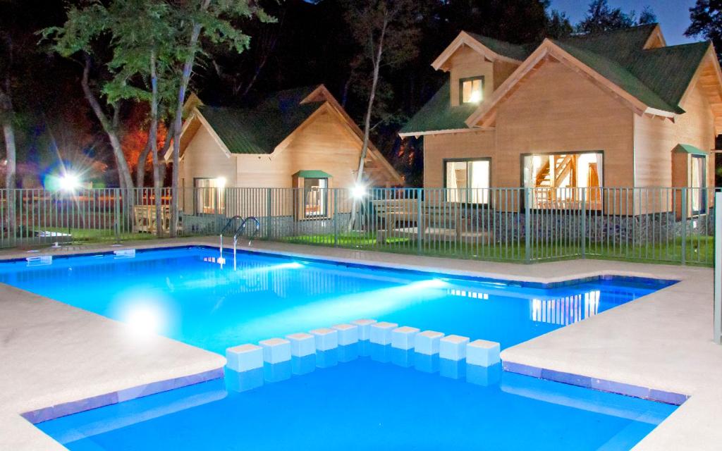 a swimming pool in front of a house at night at Cabanas y Lodge Los Hualles in Las Trancas