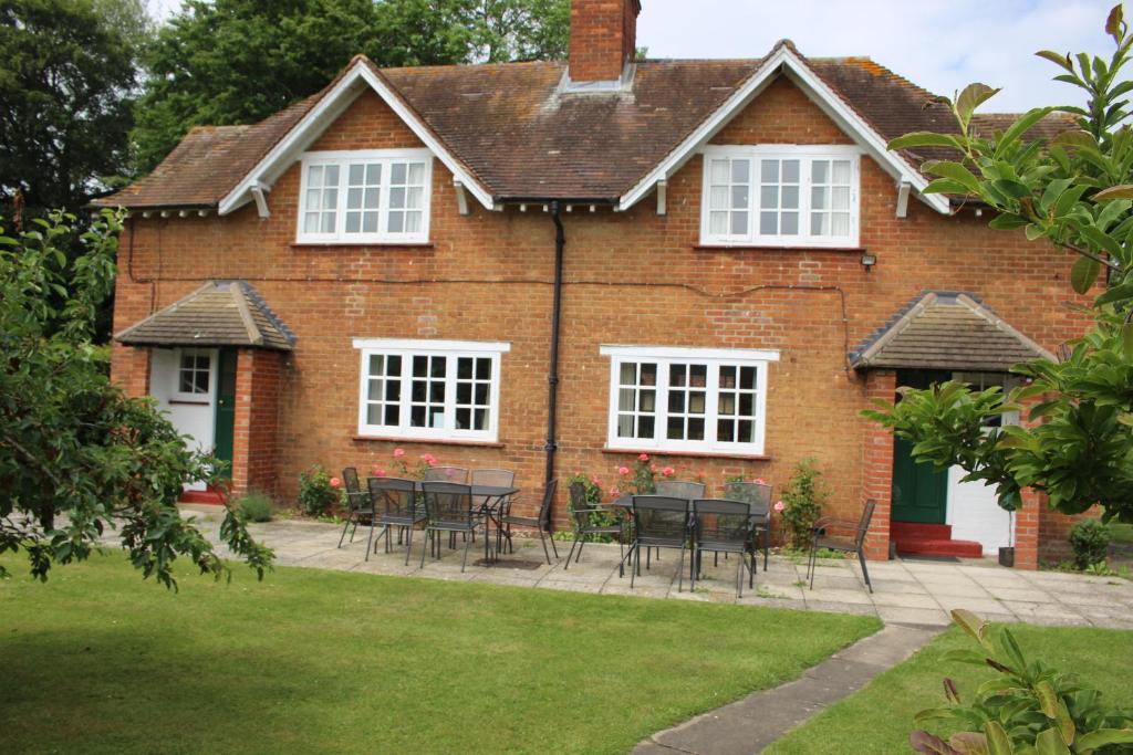 una casa in mattoni rossi con tavoli e sedie nel cortile di The Gillett's Cottage a Wantage