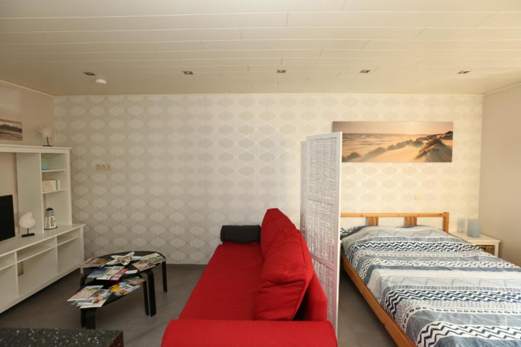 um quarto com uma cama e um sofá vermelho em de Zeester em Bredene-aan-Zee