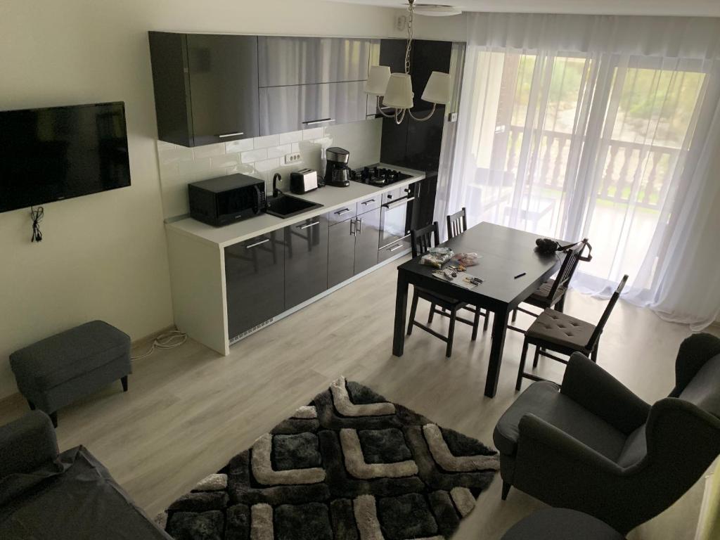 a living room with a table and a kitchen at APARTAMENT GOLDEN ROSE 2 in Buşteni