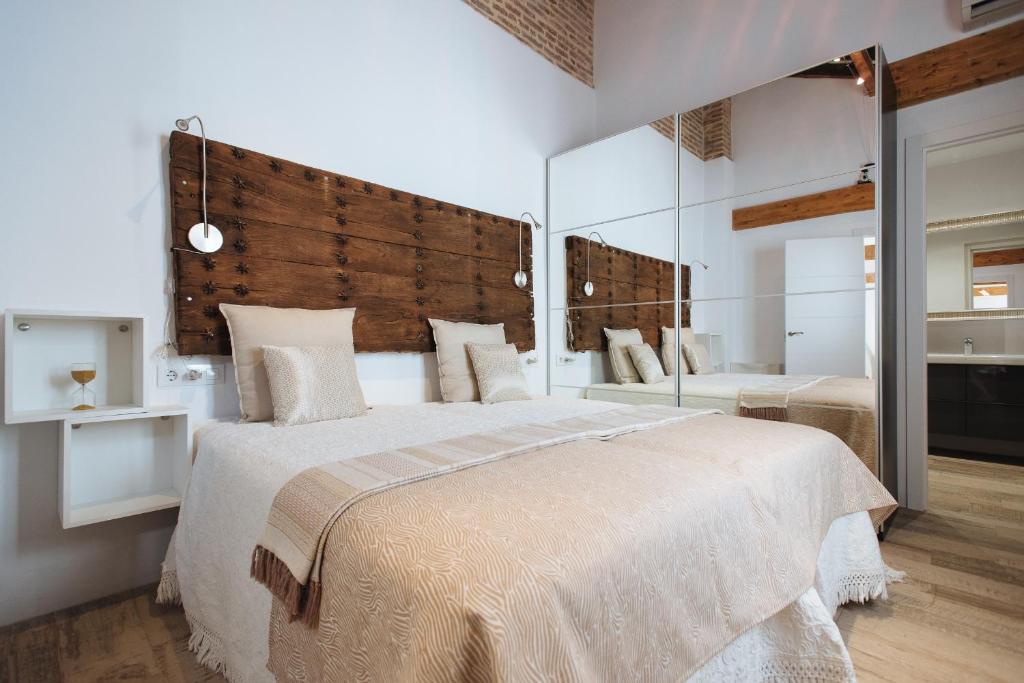 - une chambre avec un grand lit et un grand miroir dans l'établissement Casa Higuerón, à Séville