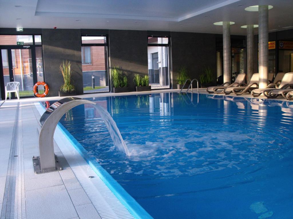 a large swimming pool in a hotel with chairs at Apartament Bałtyk Polanki Park in Kołobrzeg