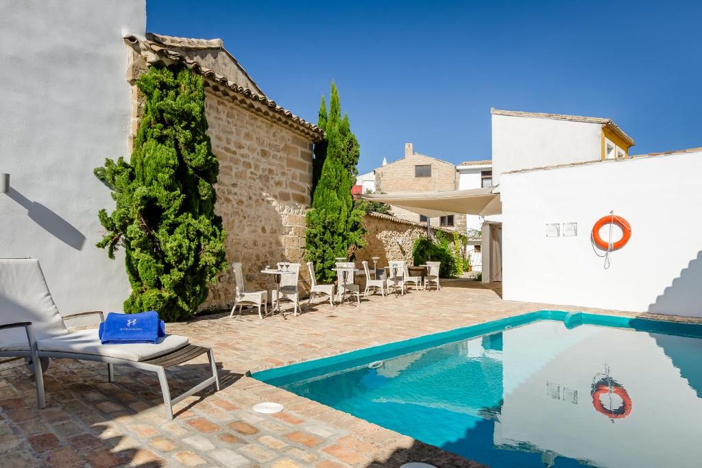 una piscina en un patio con sillas y un edificio en YIT La Casona del Arco en Baeza