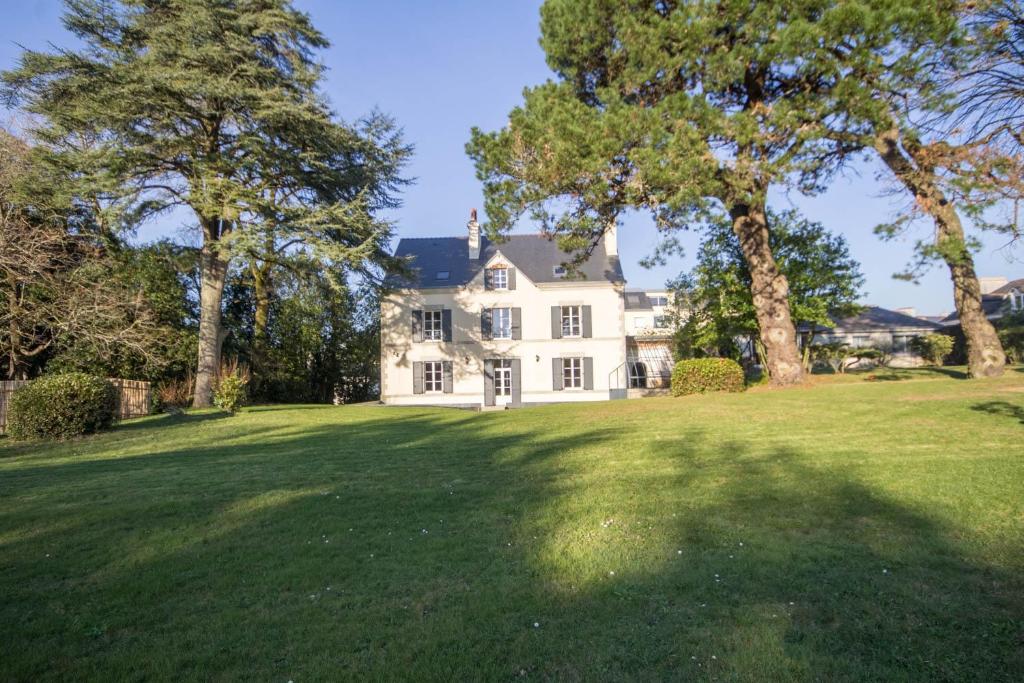 een groot wit huis met bomen in de tuin bij Villa des Mimosas in Muzillac