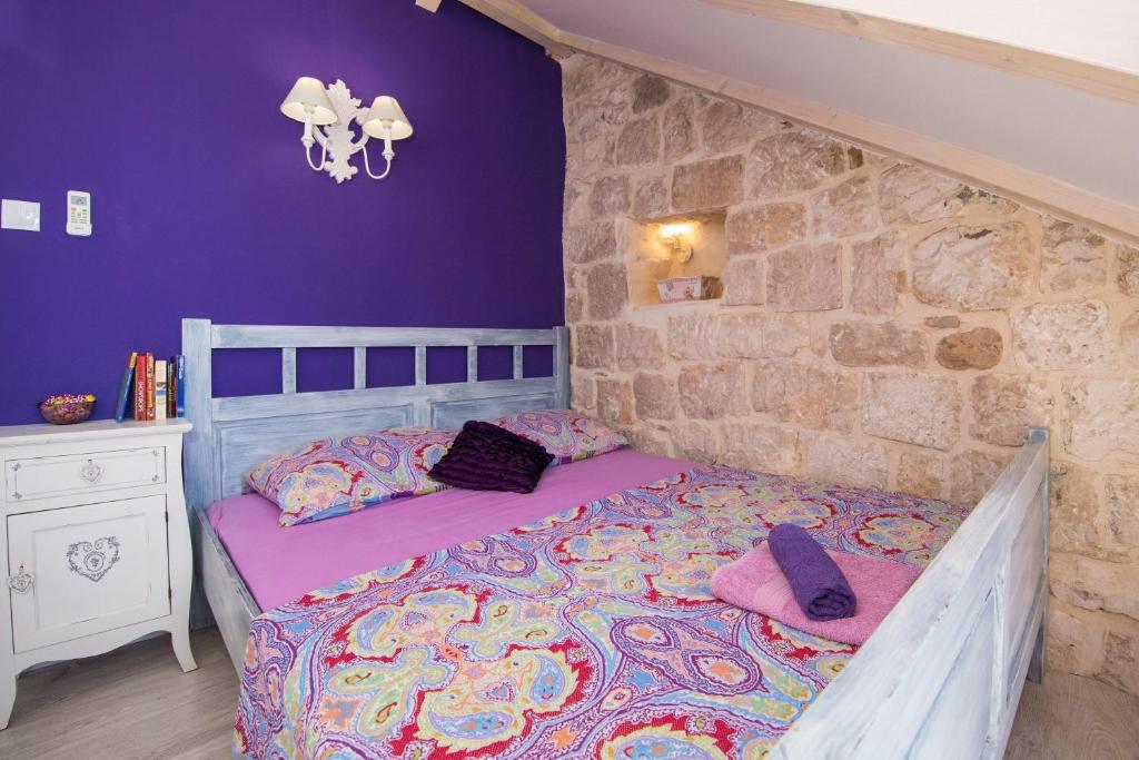 a bedroom with a bed and a stone wall at Gugilly Old Town Haven in Dubrovnik