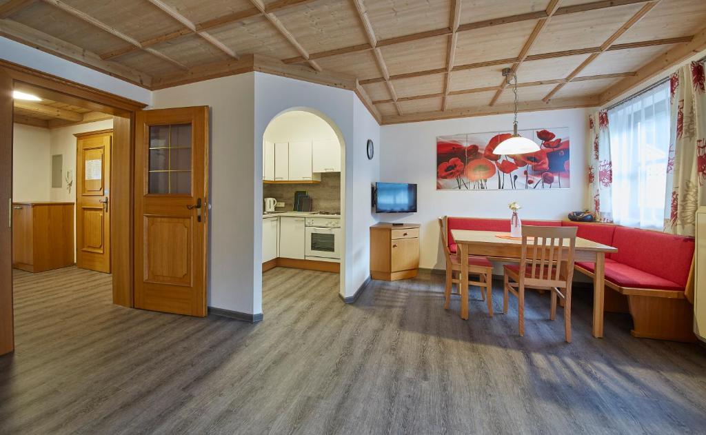 Appartements Living Saalbach في سالباخ هينترغليم: غرفة معيشة مع طاولة وأريكة حمراء