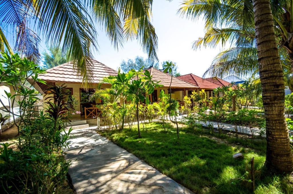 a resort with palm trees in front of a building at Fantastic Cottages in Gili Meno