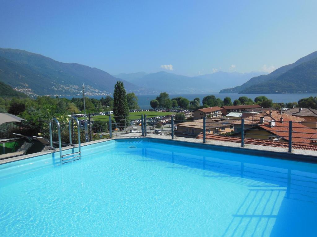 a large swimming pool with mountains in the background at Hotel Giardino in Cannobio