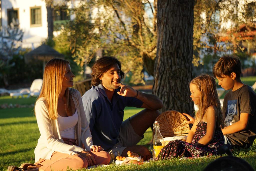 a group of people sitting on the grass in a park at Vale d'El Rei Hotel & Villas in Carvoeiro
