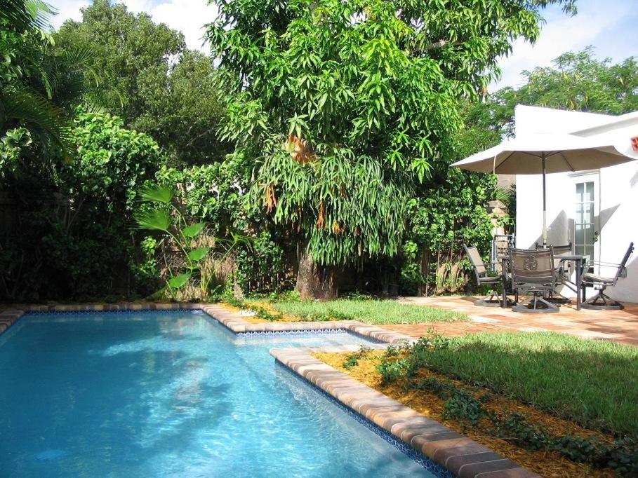 uma piscina num quintal com um guarda-chuva em Historic Cottage With Private Pool! Home em West Palm Beach