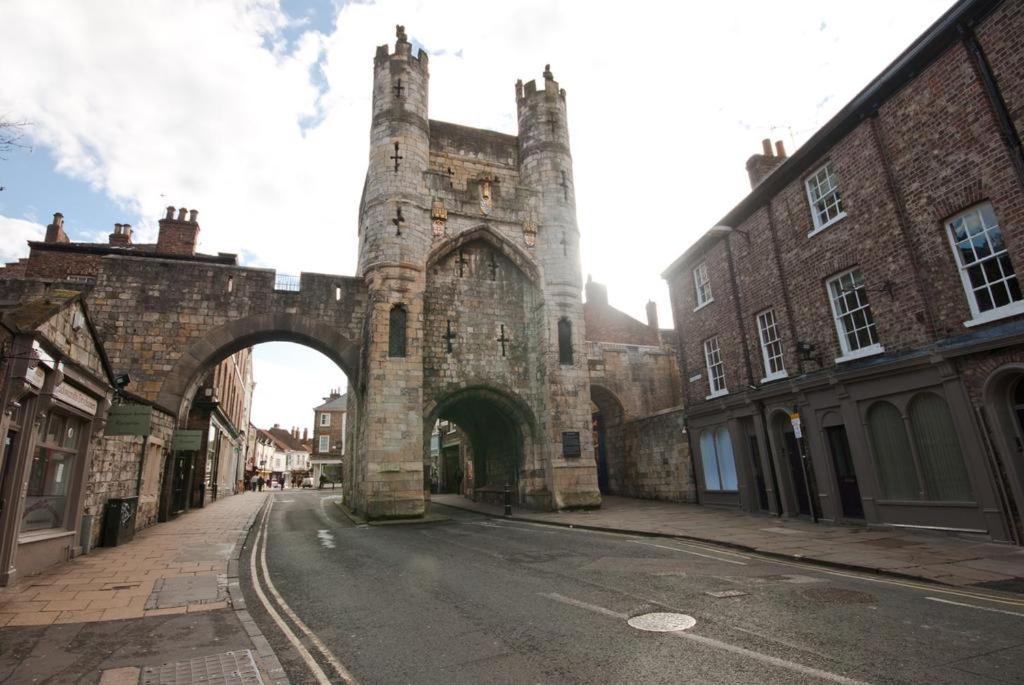 an old stone building with an arch in a street at 7 Monk Bar Court YORK in York