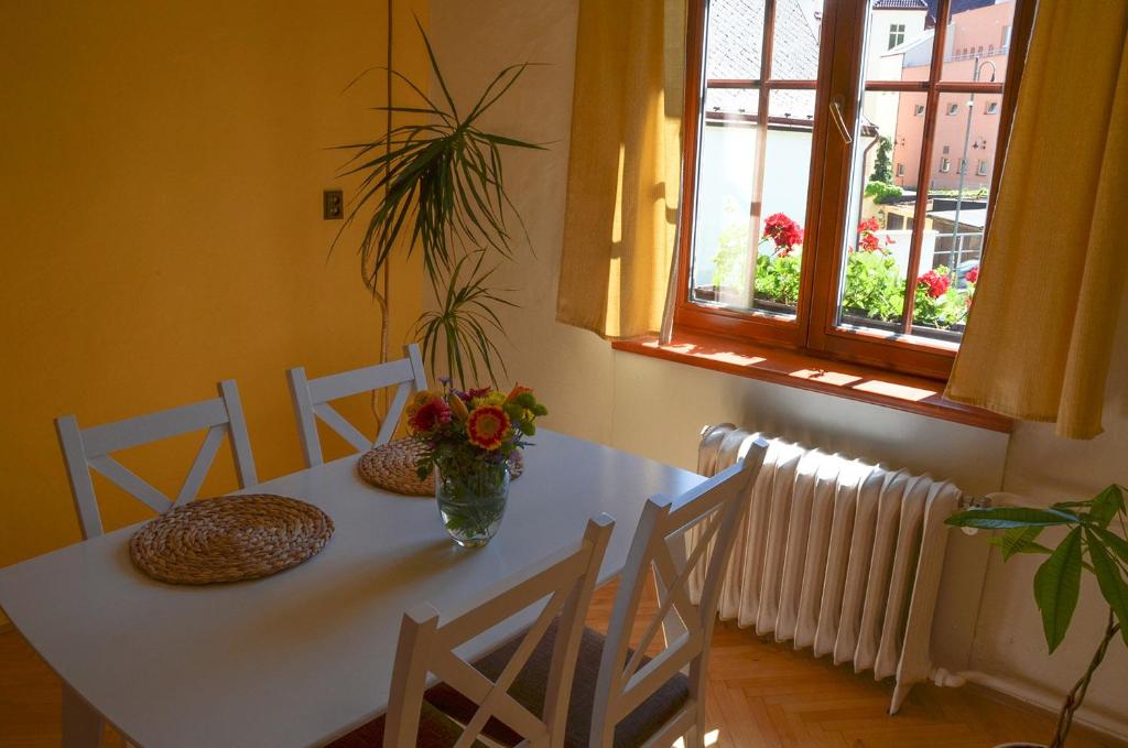 Una mesa blanca con un jarrón de flores. en Ubytování u lípy, en Náchod