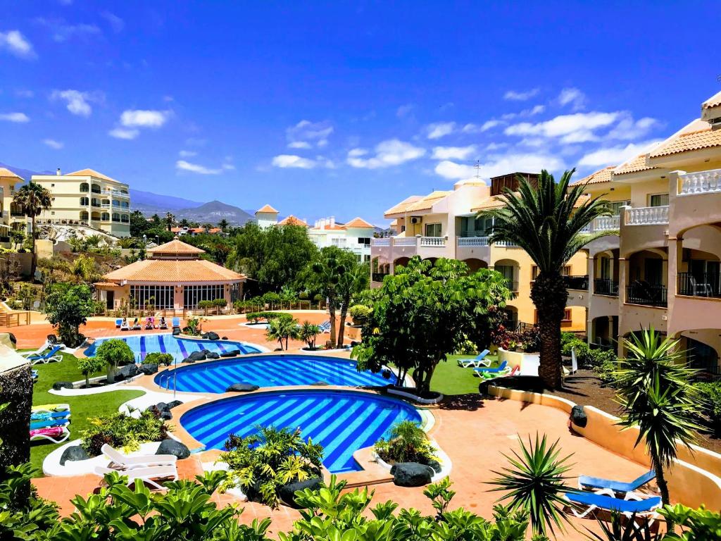 um resort com várias piscinas e palmeiras e edifícios em Away but Home em San Miguel de Abona