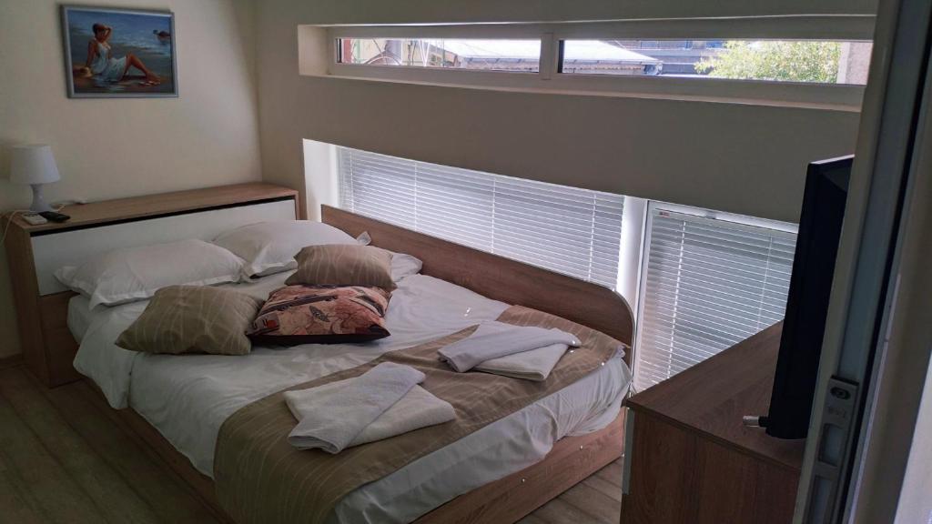ein Schlafzimmer mit einem Bett mit Kissen und einem Fenster in der Unterkunft Къща Корона in Warna