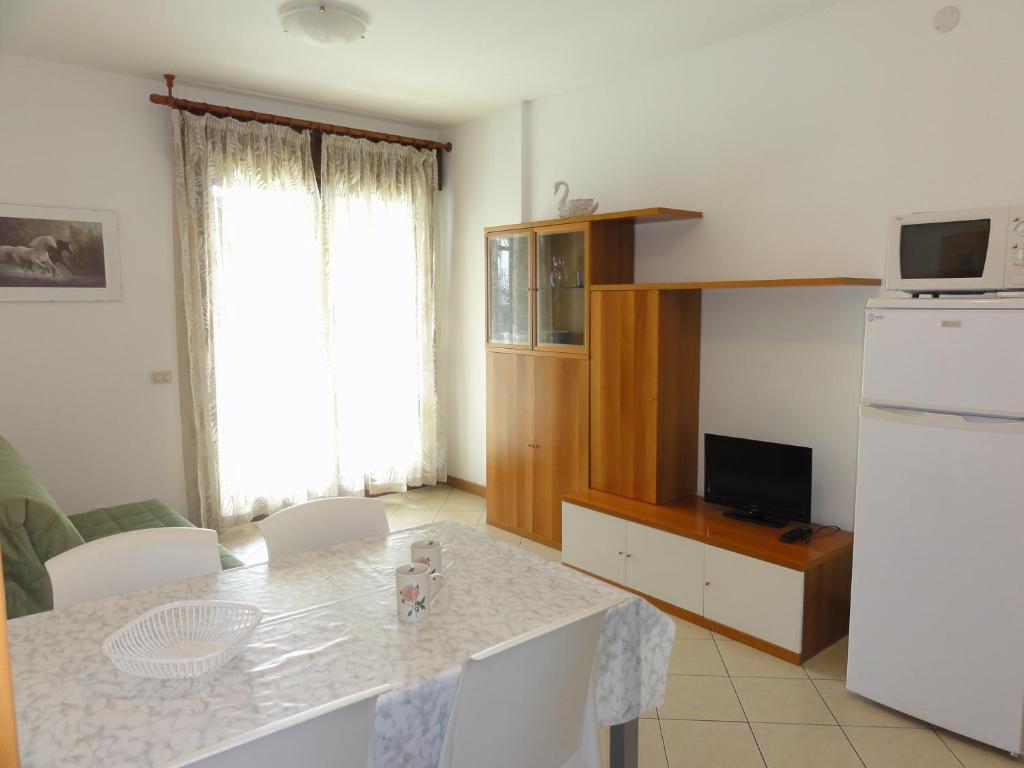 een woonkamer met een tafel en een keuken bij Albanella - Appartamenti in Bibione