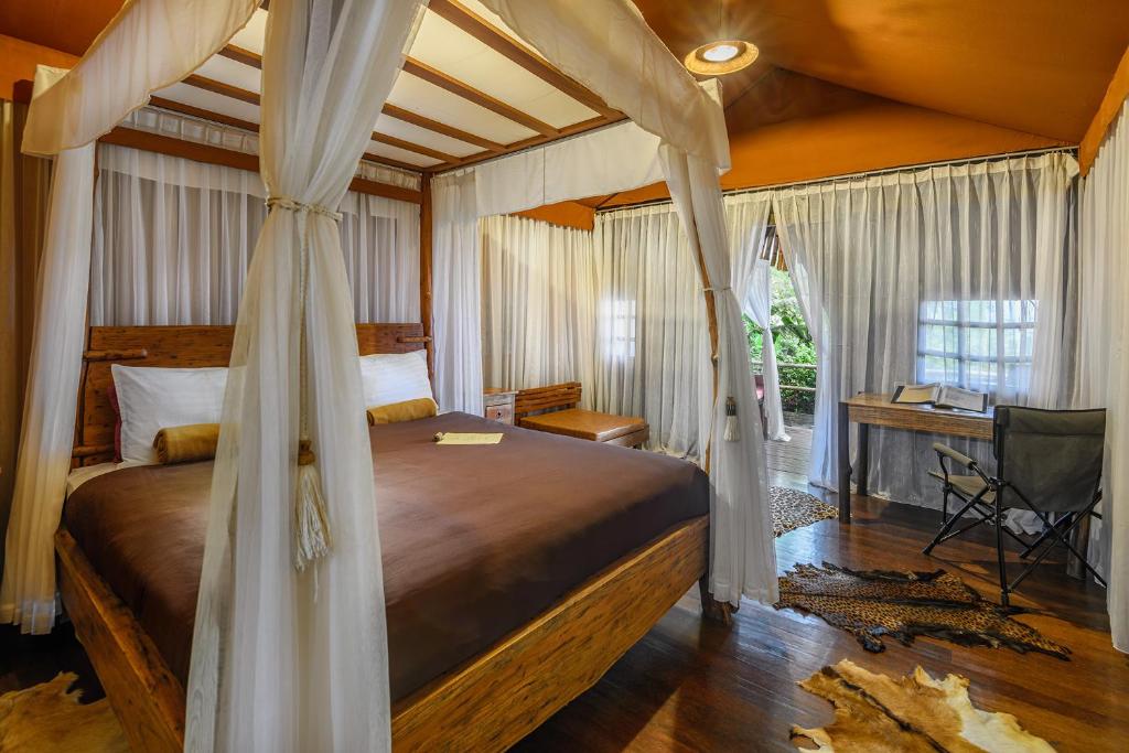 sypialnia z łóżkiem z baldachimem i biurkiem w obiekcie Sang Giri - Mountain Glamping Camp w mieście Jatiluwih