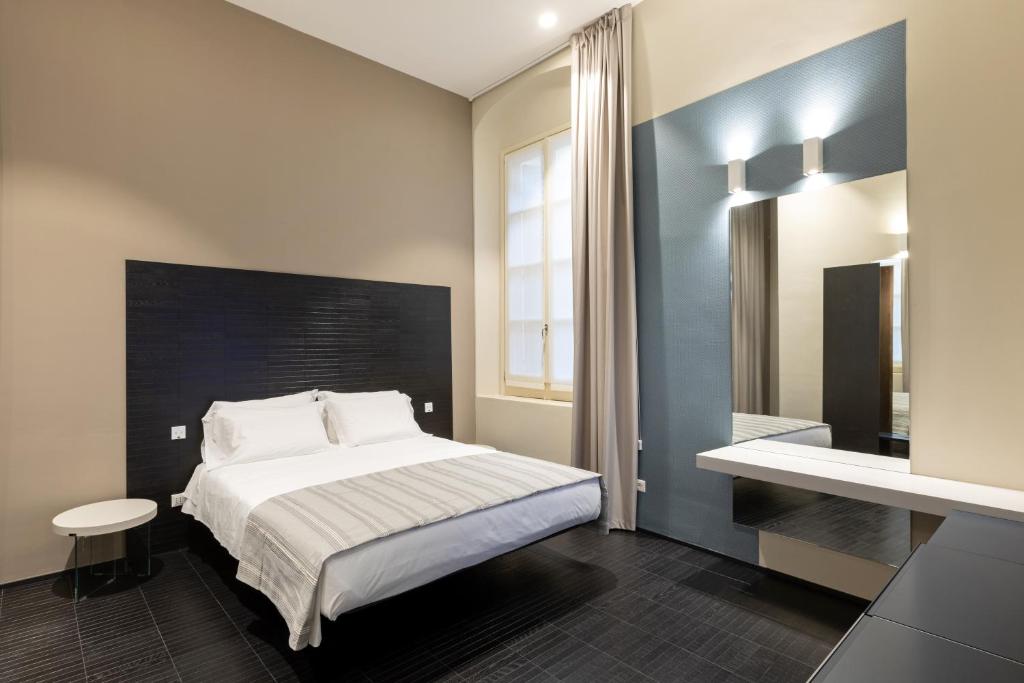 - une chambre avec un grand lit et un miroir dans l'établissement Salina Luxury Suites, à Parme