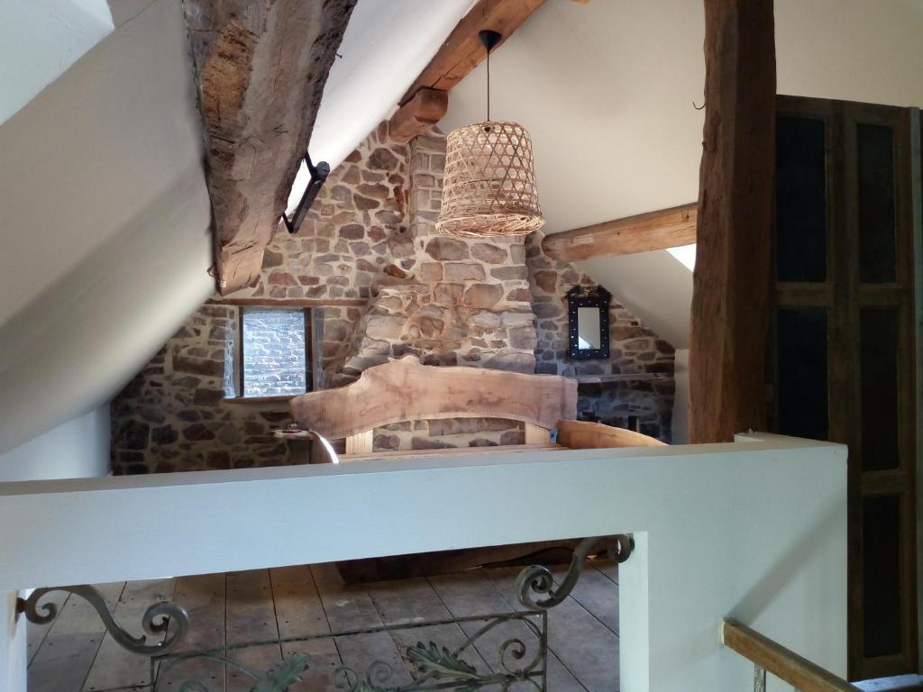 an attic room with a stone wall and a chandelier at Maison de gesves in Gesves